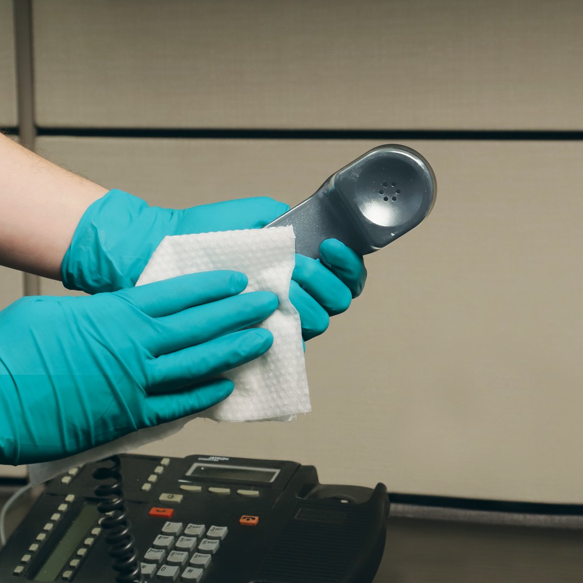 Worker disinfecting a mobile phone screen with a MEDAPHENE PLUS wipe