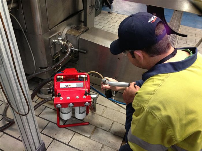 Maintenance technician sampling oil from a handheld filtration system